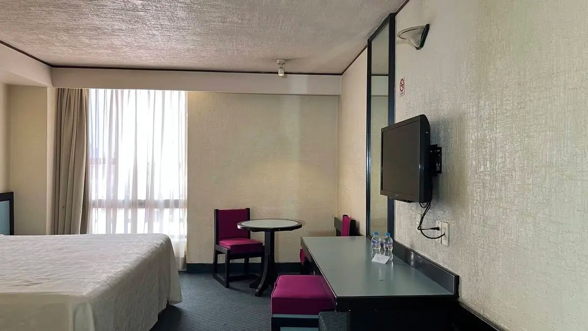 Habitación sencilla estándar con cama king size con colores cálidos y una mesa y una televisión en la pared